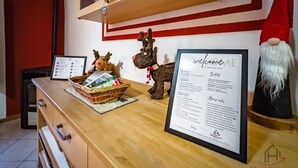 Una mesa de recepción con un cartel de bienvenida enmarcado, un pequeño árbol de Navidad y una decoración de gnomo.