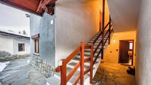Una escalera de piedra que lleva a una puerta de madera, una pared de piedra y un ventanal pequeño.