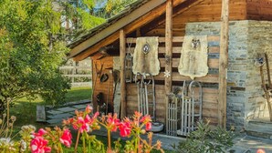 Una cabaña rústica con paredes de piedra, vigas de madera y un porche con objetos colgantes.