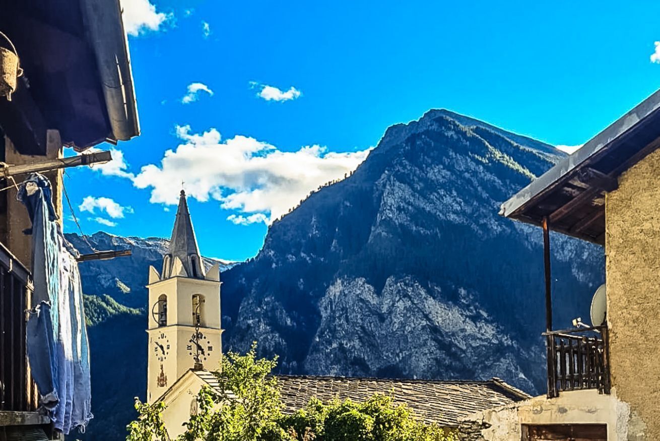 Un pueblo de montaña con una iglesia y montañas al fondo.