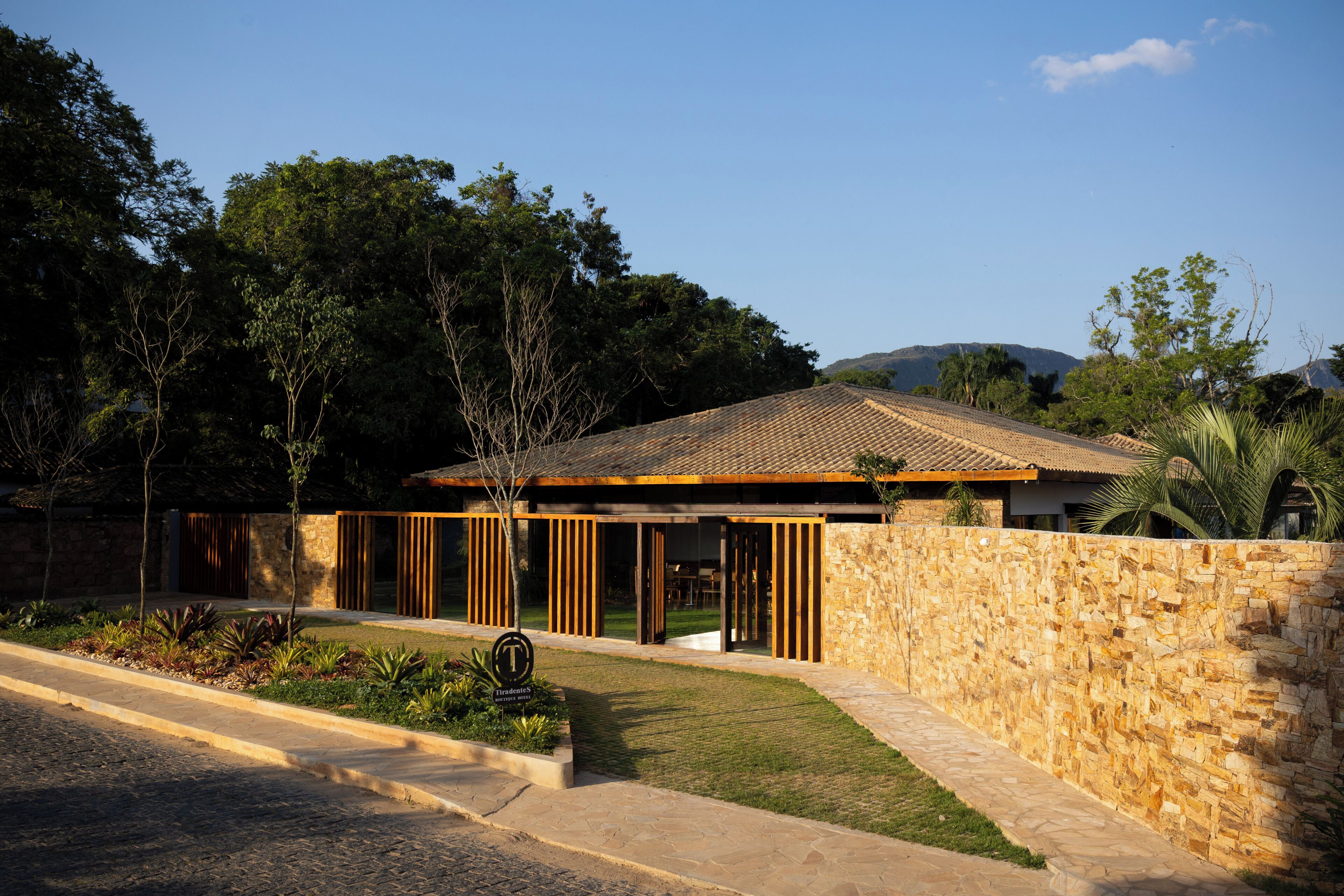 A modern hotel with a stone facade, wooden slats, and a tiled roof.