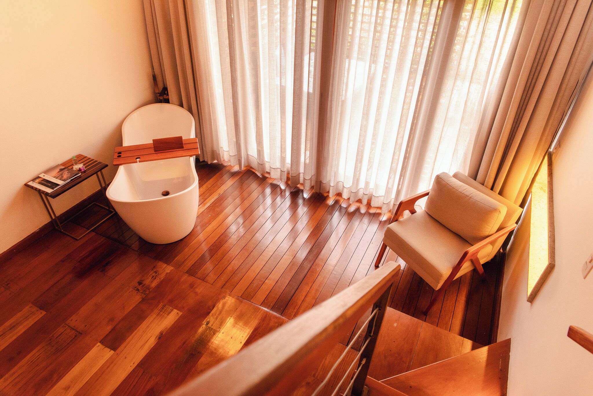 Um interior moderno com piso de madeira, vaso sanitário branco, sofá bege e escada.