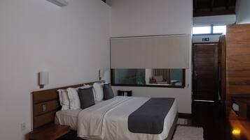 Un dormitorio con cama, mesitas de noche, una ventana con vistas y una puerta de madera.
