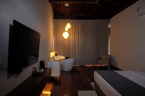 Een moderne hotelkamer met een groot bed, een bureau, een stoel, een badkamer en een grote spiegel.