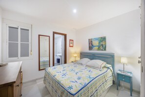 Ein Schlafzimmer mit Bett, Nachttisch, Lampe und einem Bild an der Wand.