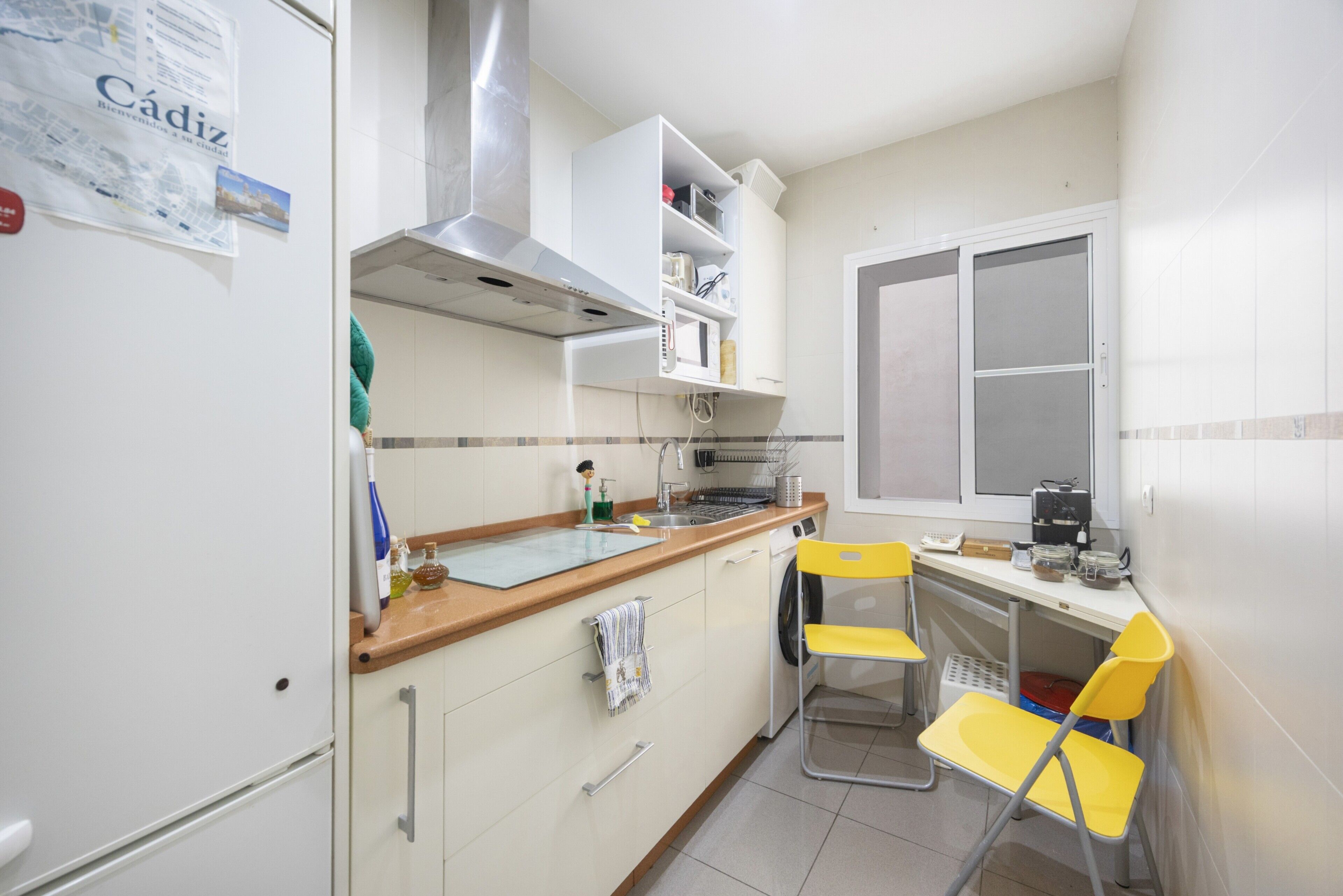 A kitchen with a microwave, toaster, and sink. There is a window with blinds and a door.
