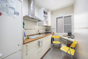 Eine Küche mit Mikrowelle, Toaster und Spüle. Ein Fenster mit Jalousien und eine Tür sind vorhanden.