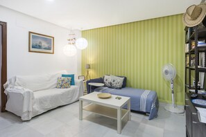 Ein Zimmer mit einem weißen Sofa, einem blauen Sofa, einem kleinen weißen Tisch und einer Wand mit grünen Streifen.