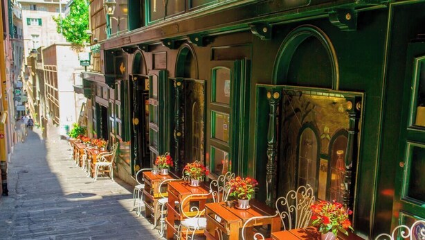 A narrow street with outdoor seating and green awnings. - [Comfort Suite] Airport 5 min • A/C • Smart TV (Genova)
