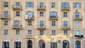 A multi-story building with balconies, arched windows, and storefronts with signage. - [Comfort Suite] Airport 5 min • A/C • Smart TV (Genova)