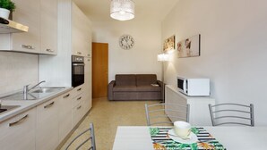 A compact kitchen with a dining area, a sofa, and a microwave. - GuestHost - Central Flat - Arno, Station and Duomo (Firenze)