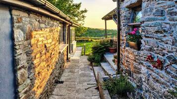 A stone pathway leading to a building with a wooden porch and flower pots.