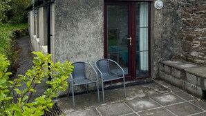 A small building with a stone exterior, a glass door with a red frame, and a satellite dish.