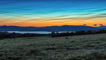 A landscape with a body of water, rolling hills, and a clear sky.