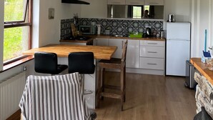 A modern kitchen with a wooden table, chairs, a microwave, and a refrigerator.