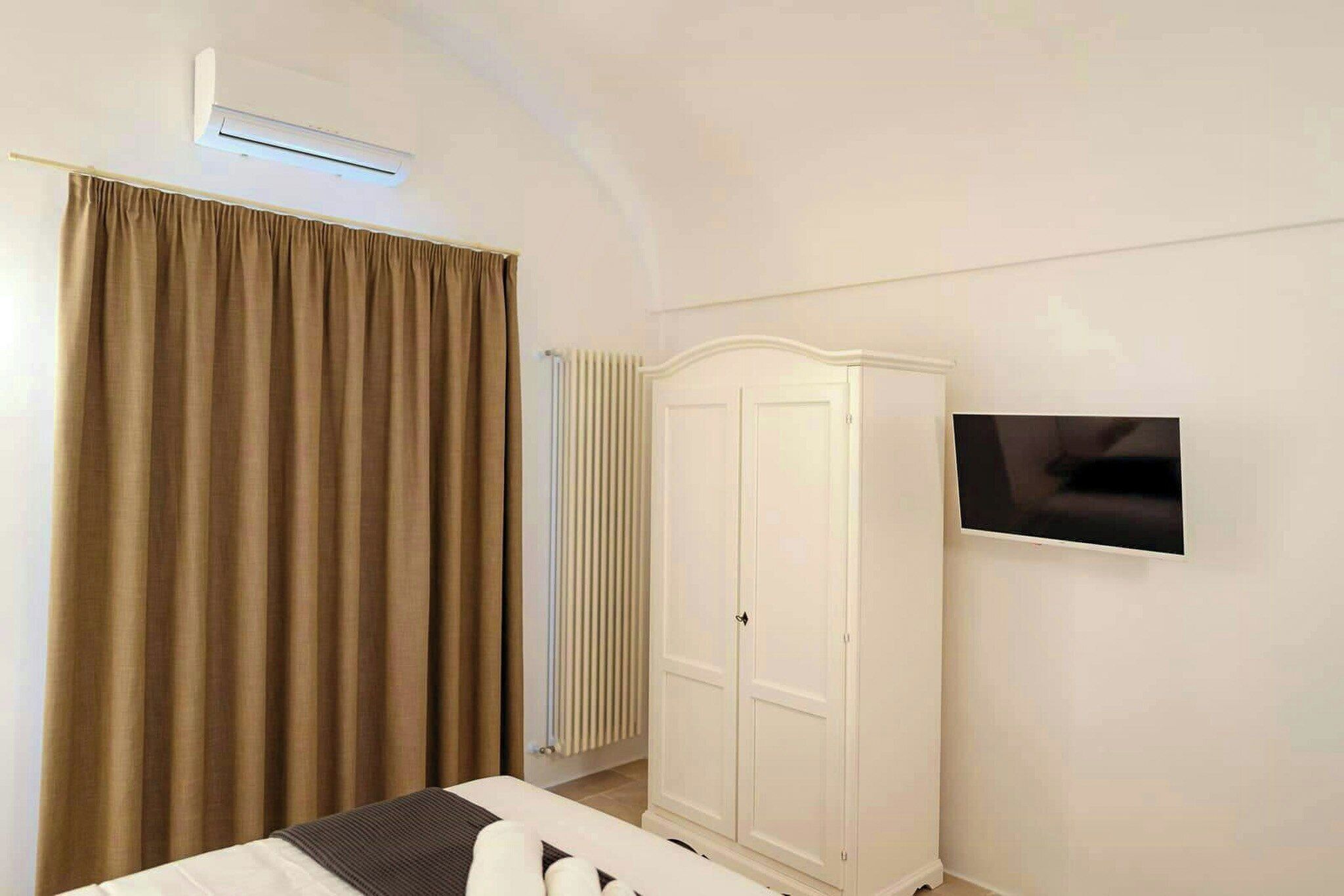 Une chambre à coucher comprenant un lit, une armoire, un radiateur et un téléviseur fixé au mur.