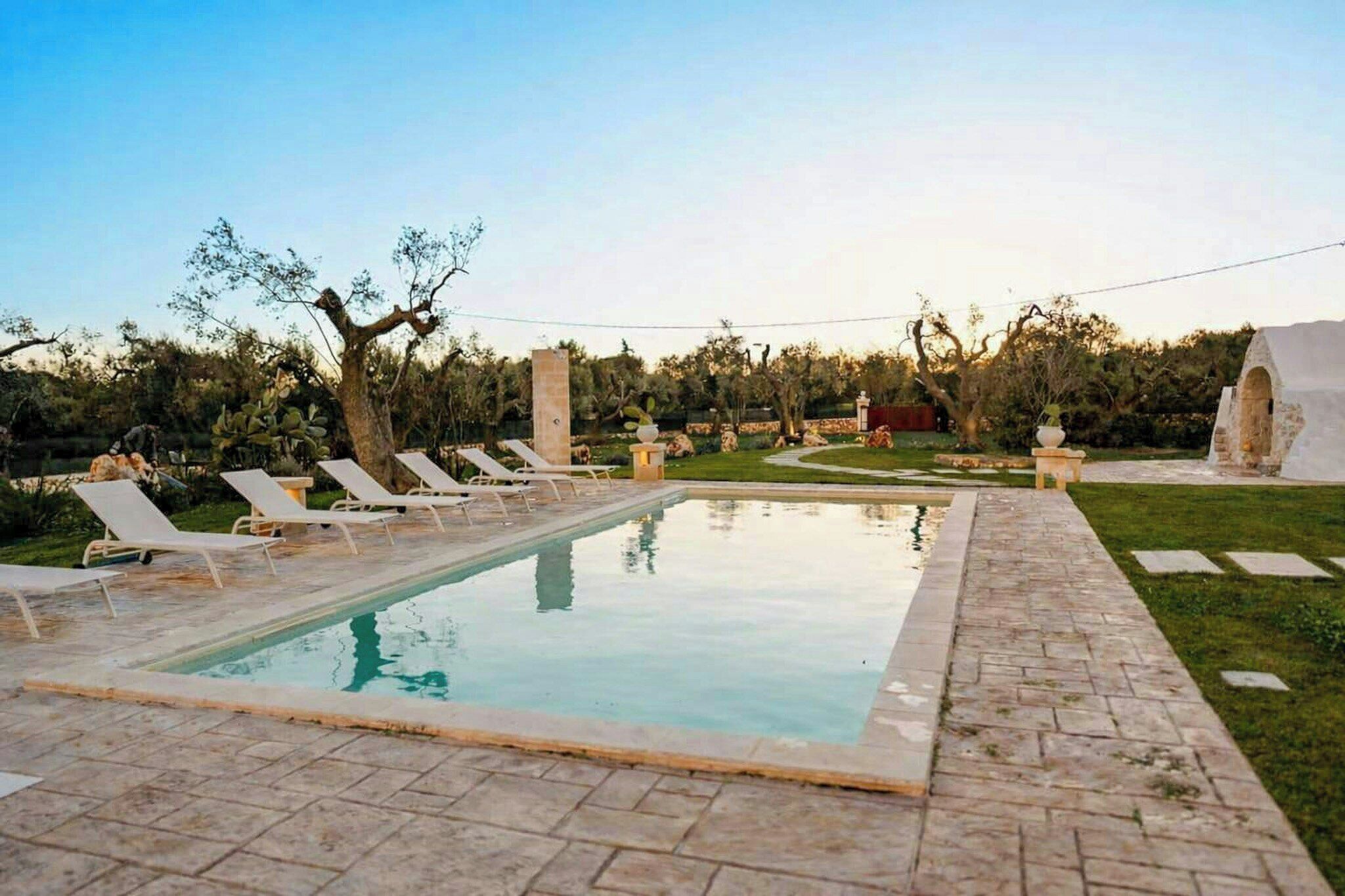 A rectangular pool with lounge chairs and a stone pathway.
