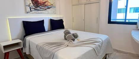 A bedroom with a bed, a nightstand, a painting, a wardrobe, and a window.