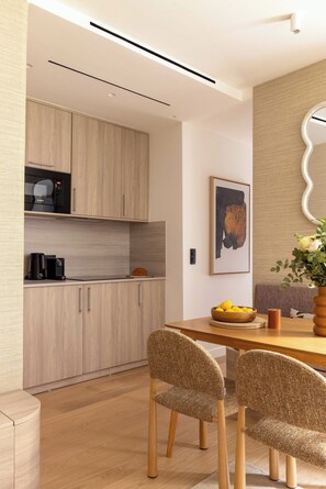 A modern kitchen with wooden cabinets, a dining table with two chairs, and a wall-mounted mirror. - Refined Apartment a/c 1ch/4p - Champs de Mars (Paris)