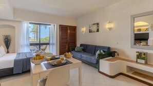 Una habitación de hotel moderna con cama, zona de comedor, sofá y un amplio ventanal con vistas.