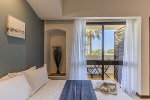 A hotel room with a bed, a painting on the wall, a plant, and a balcony with a table and chairs. - #342 Cozy Studio in Belavista | Pool & Central (Albufeira)