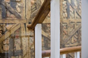 A wooden staircase with white balusters and a textured wall in the background. - GuestReady - InPorto Building - Room 3 (Porto)