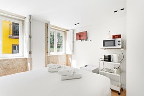 Ein Hotelzimmer mit Bett, Fernseher, Mikrowelle und einer Ablage mit Küchenutensilien.