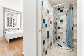 A bathroom with a shower, a bed, and a window. - GuestReady - InPorto Building - Room 1 (Porto)