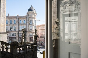 A view of a historic building with a dome and ornate architecture, seen through a window with a decorative door. - GuestReady - InPorto Building - Room 1 (Porto)