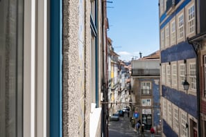 A narrow street with buildings on either side, a clear sky, and a few pedestrians. - GuestReady - InPorto Building - Room 2 (Porto)