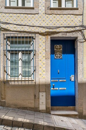 A building with a blue door, numbered 102, and a window with metal bars. - GuestReady - InPorto Building - Room 2 (Porto)