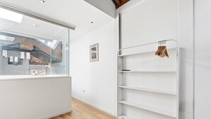 A modern interior with a glass wall, white shelving unit, and a framed picture on the wall. - GuestReady - InPorto Building - Room 7 (Porto)