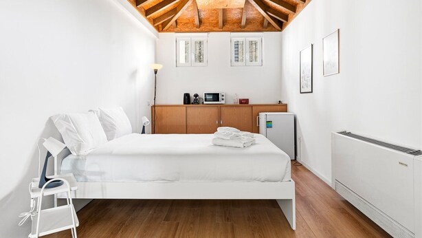 A bedroom with a wooden ceiling, a bed, a small kitchenette, and a radiator. - GuestReady - InPorto Building - Room 7 (Porto)
