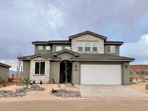 A two-story house with a garage, a stone facade, and a landscaped front yard. - Paseos Pool Oasis | Outdoor Pool & Hot Tub (Washington)