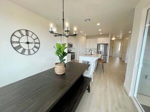 A modern kitchen with a dark wooden countertop, a large wall clock, and a hanging light fixture. - Paseos Pool Oasis | Outdoor Pool & Hot Tub (Washington)