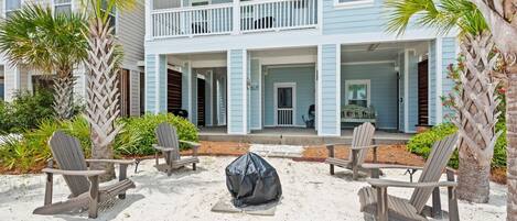 A beachfront property with a covered seating area, a covered fire pit, and a two-story building with balconies.