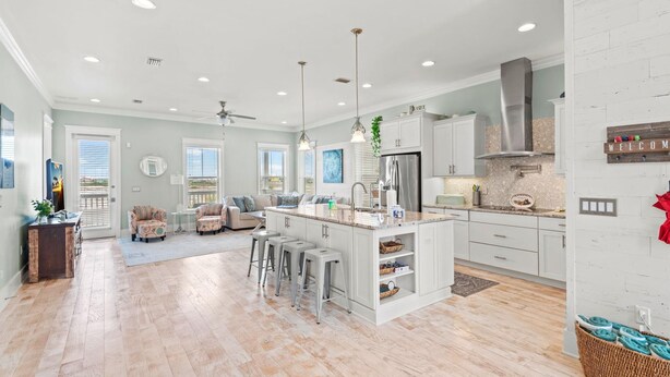 A spacious kitchen with a central island, bar stools, and a dining area with a sofa and chairs. - Sea Haven (Navarre)