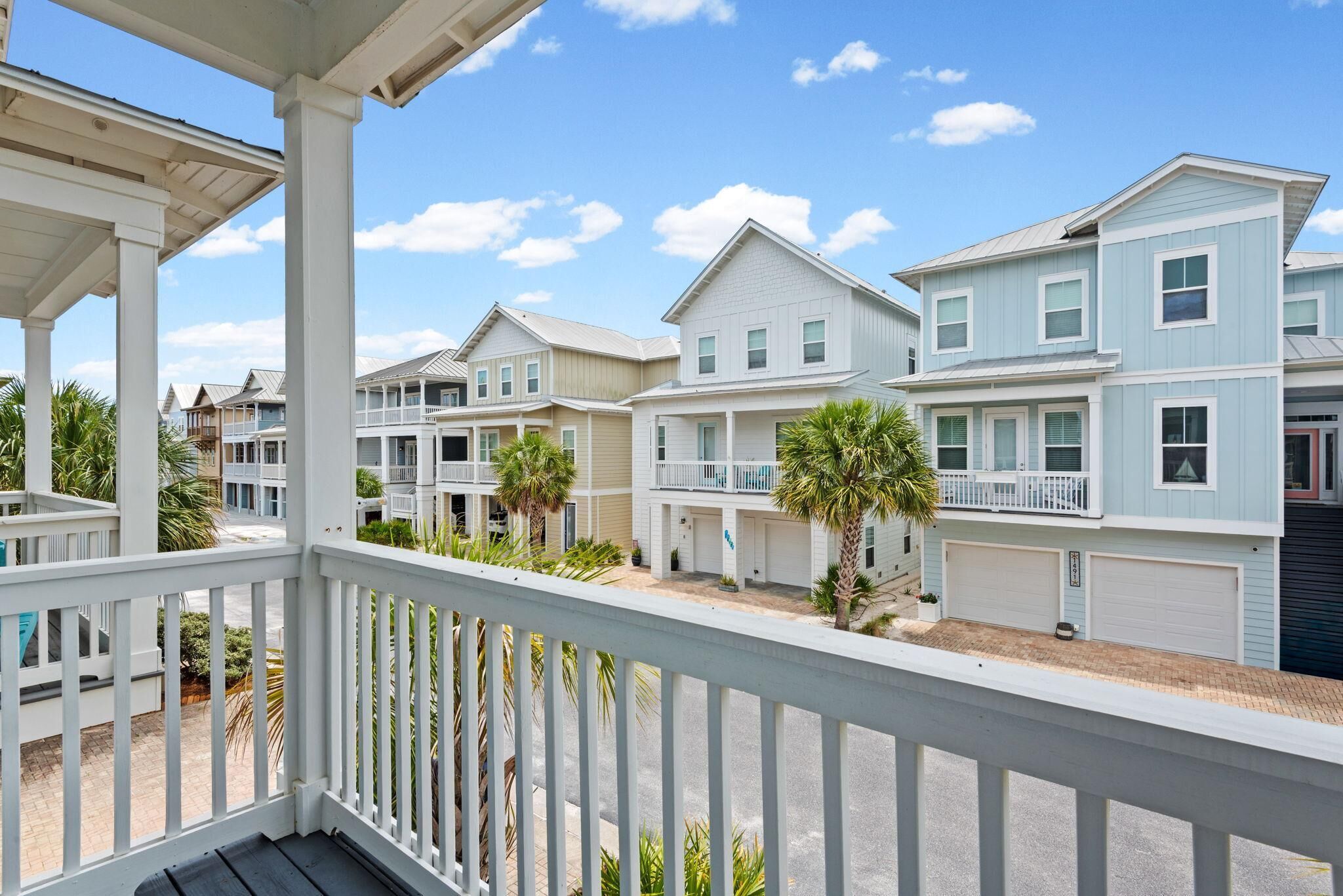 A row of coastal-style houses with balconies, a covered porch, and a clear sky.