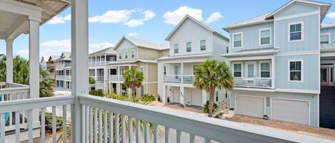 A row of coastal-style houses with balconies, a covered porch, and a clear sky.