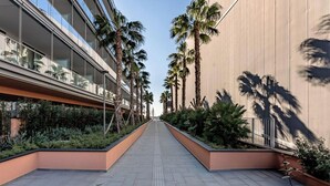 Un bâtiment moderne doté d’une allée centrale bordée de palmiers et de verdure.