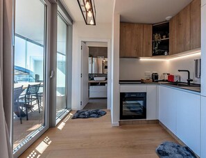 Eine moderne Küche mit Einbauofen, ein Essbereich mit Tisch und Stühlen sowie eine Glastür, die zu einem Außenbereich führt.