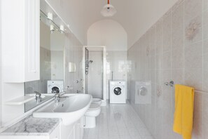 Een moderne badkamer met een wastafel, toilet en wasmachine.