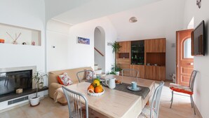 Un salon moderne doté d’une cheminée, d’une table à manger et d’un coin cuisine.
