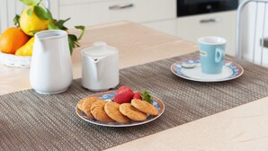 Une cuisine moderne avec une table à manger mise pour le petit-déjeuner, comprenant une assiette de biscuits, une tasse et un pichet.
