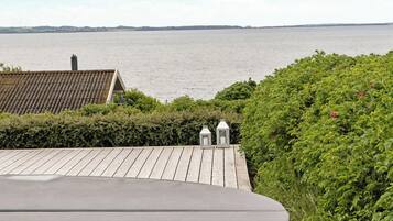 A hot tub with a view of the water and distant land.