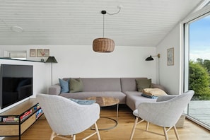 Una sala moderna con un sofá, dos sillones, un televisor y una estantería.
