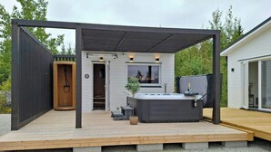 Eine Terrasse mit Whirlpool, Holztür und Fenster.