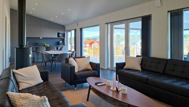 Ein modernes Wohnzimmer mit einer Couch, Sesseln, einem Couchtisch und einem Essbereich mit Tisch und Stühlen.