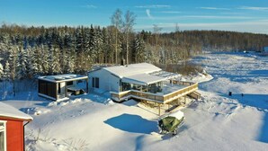 Ein modernes Haus mit einer großen Terrasse, umgeben von einem verschneiten Wald.