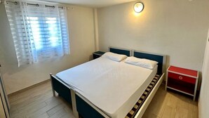 A bedroom with a bed, bedside tables, a nightstand, a red drawer unit, and a window with curtains. - Sea View Flat With a Furnished Outdoor Space (San Michele al Tagliamento)